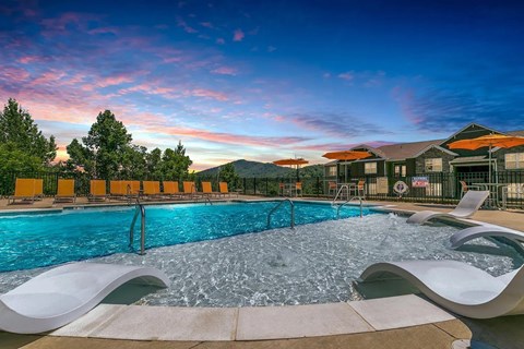 A large outdoor swimming pool with chairs and loungers.