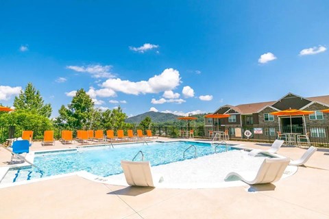 A large swimming pool surrounded by lounge chairs and trees.