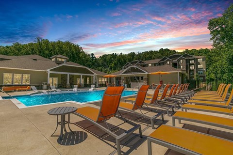 A poolside area with orange lounge chairs and a swimming pool.