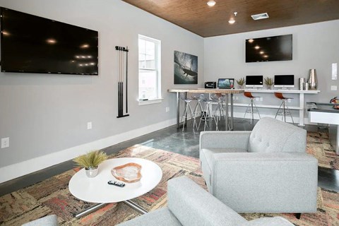 A living area with a white couch, a white coffee table, and a flat screen TV mounted on the wall.