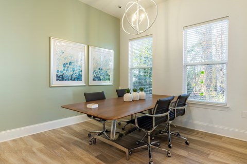 A conference room with a table, chairs, and two framed pictures on the wall.
