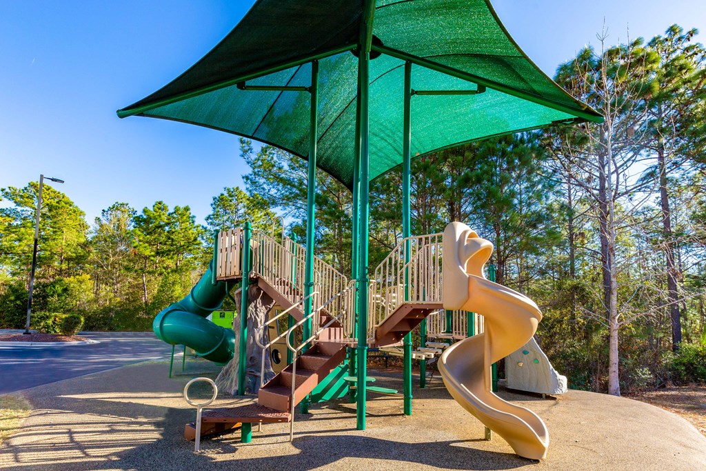 a playground with two slides and a green umbrella