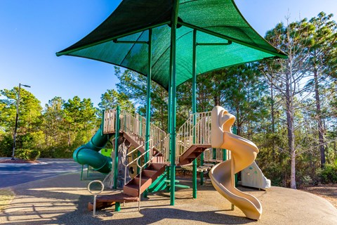 a playground with two slides and a green umbrella