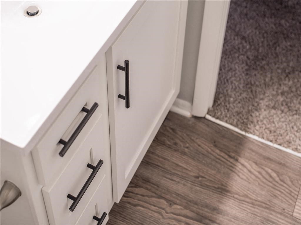 a close up of white cabinets with black handles in a bathroom