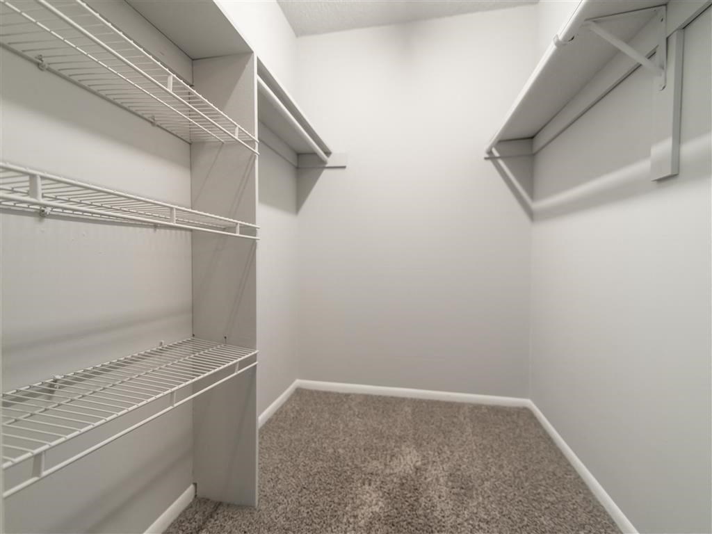 a walk in closet in a home with empty shelves