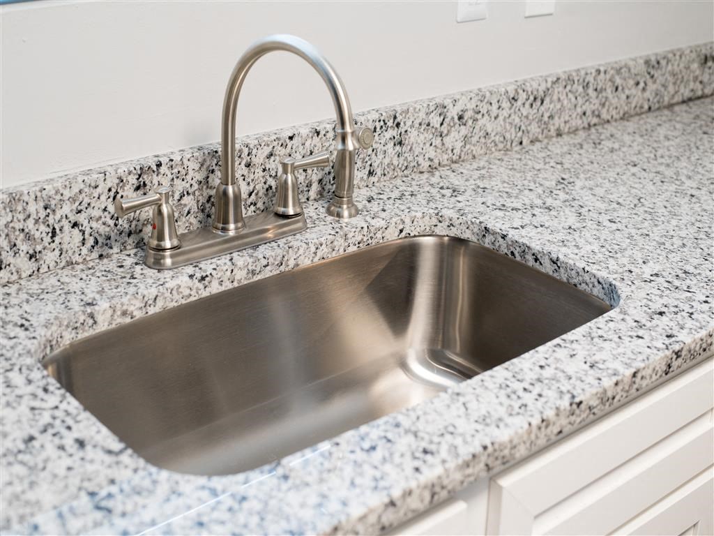 a stainless steel sink in a granite counter top