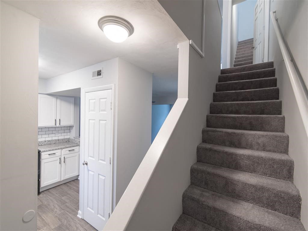a staircase in a home next to a kitchen with a white door