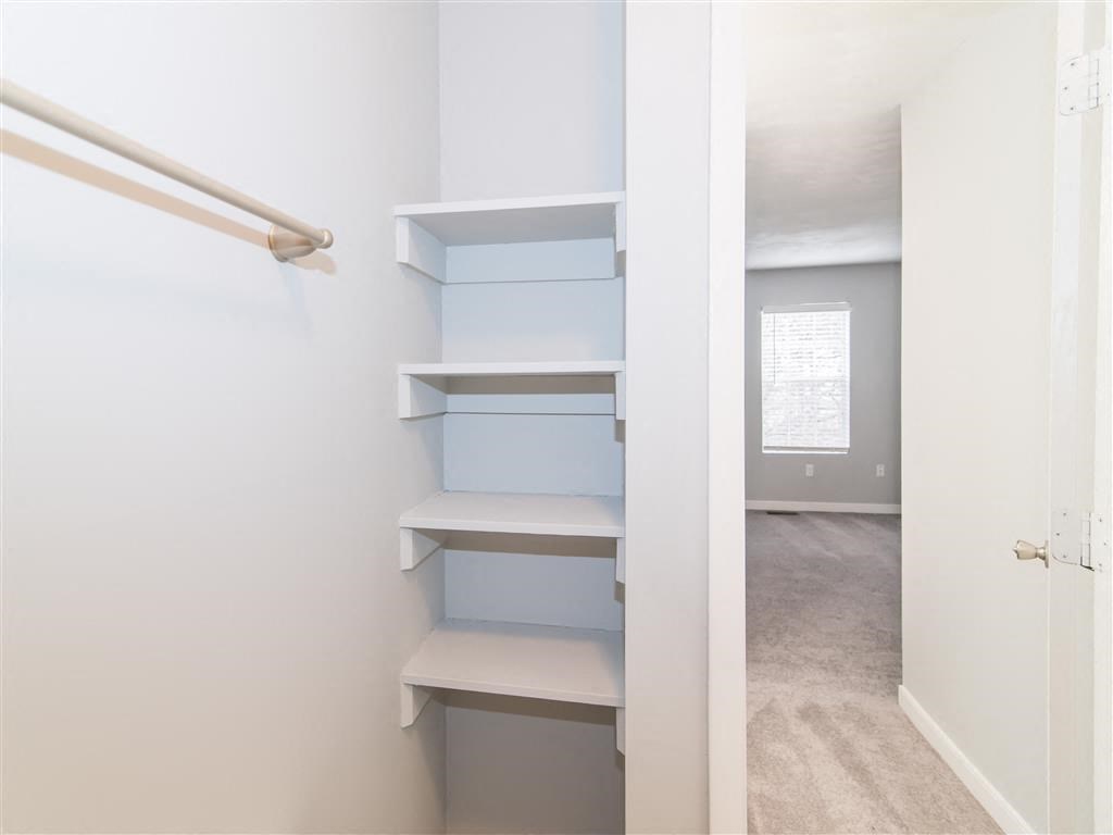 a walk in closet with shelves and a white closet door