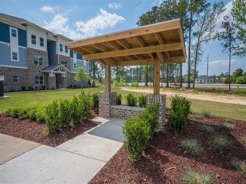a covered area with landscaping in front of an apartment building