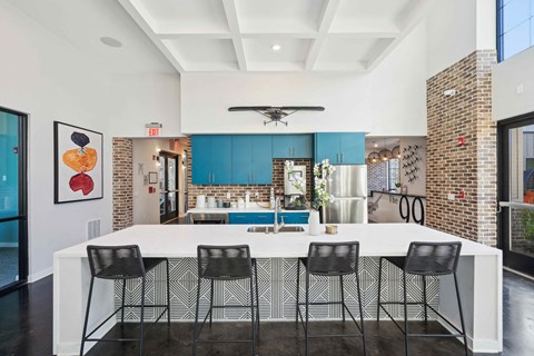 the kitchen has a large island with black chairs and blue cabinets