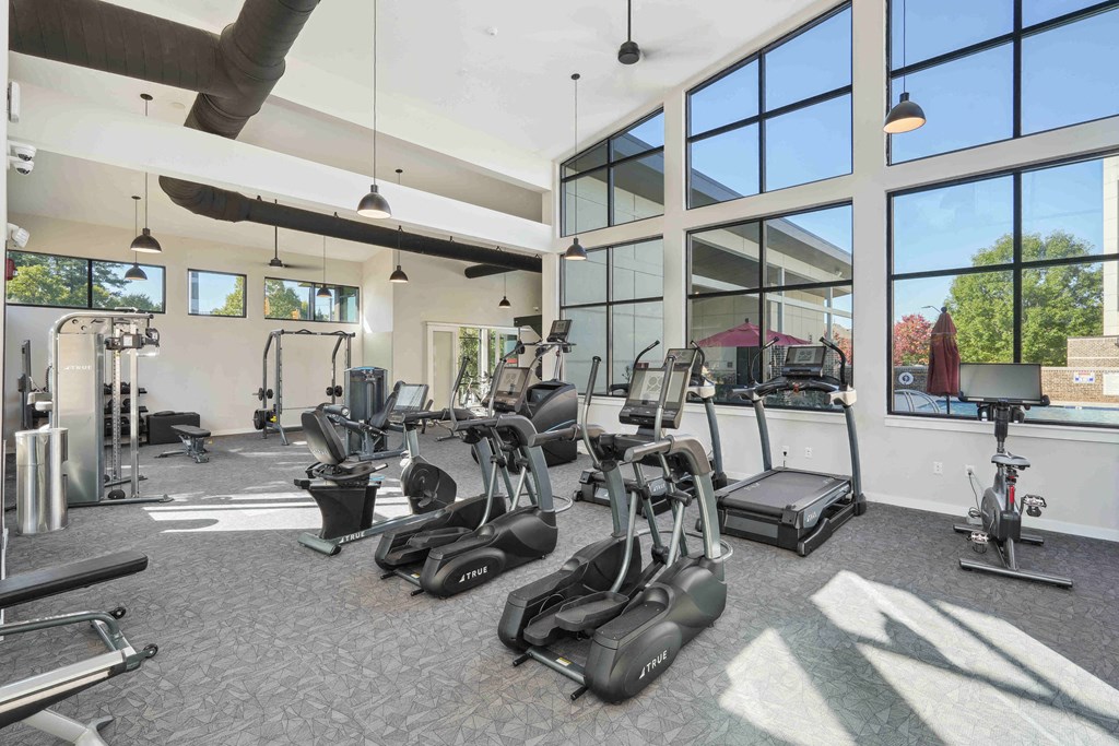 a gym with cardio equipment and windows at the estates apartments