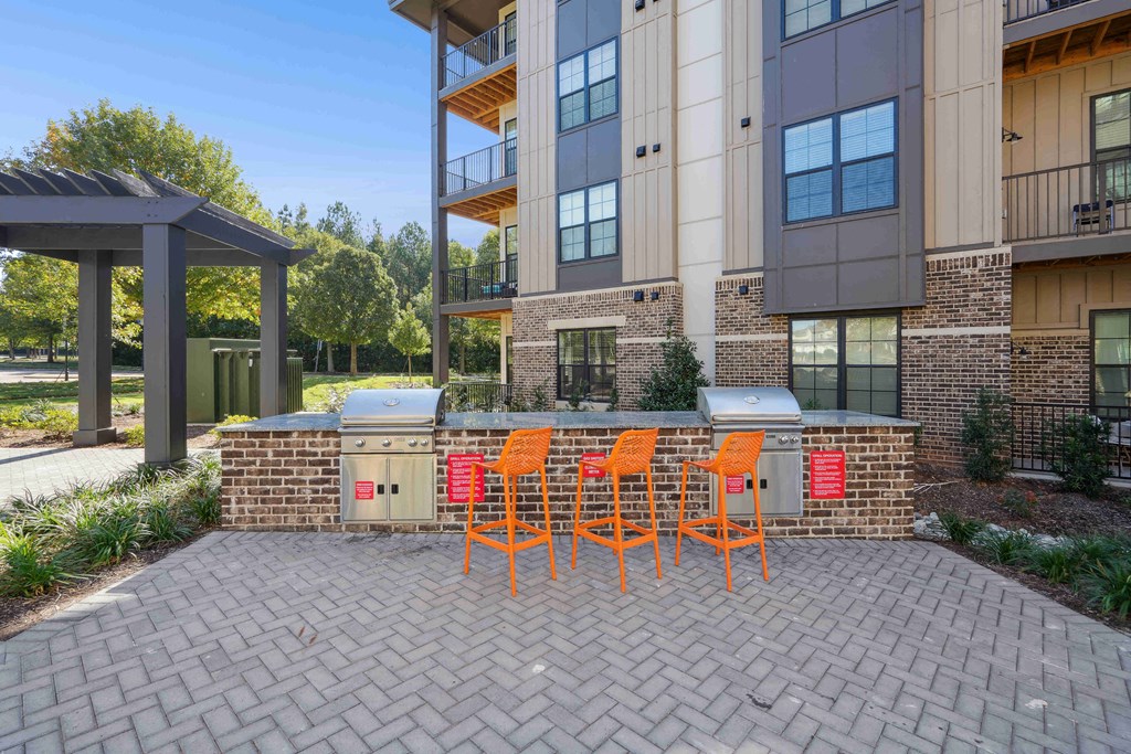 a patio with a bar and chairs in front of an apartment building