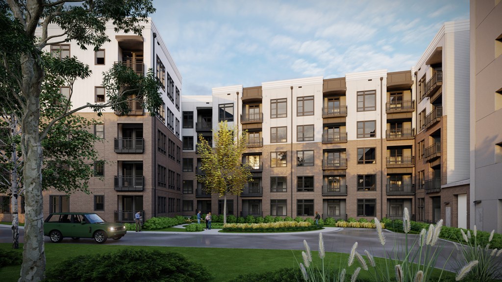 A green car is parked on the street in front of apartment buildings.
