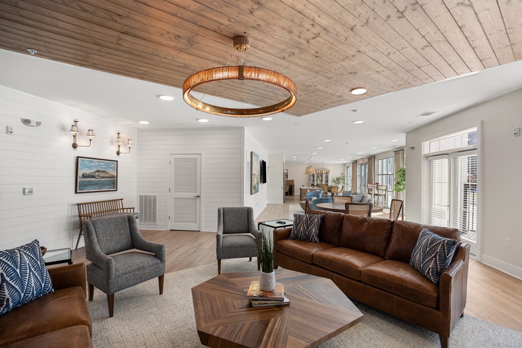 Clubhouse living room with a brown leather couch and a wooden coffee table.