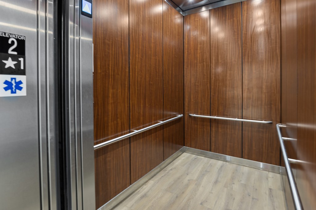 Inside the elevator with wood paneling and hand rails.