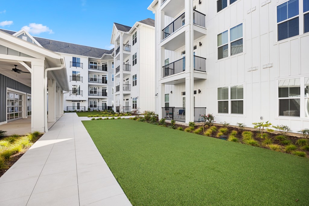 Complex exterior with a green lawn next to it and bushes.