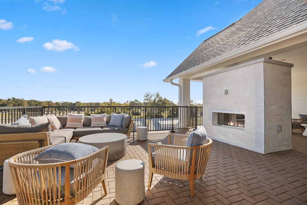 A rooftop patio with a fireplace, chairs and couch for seating.