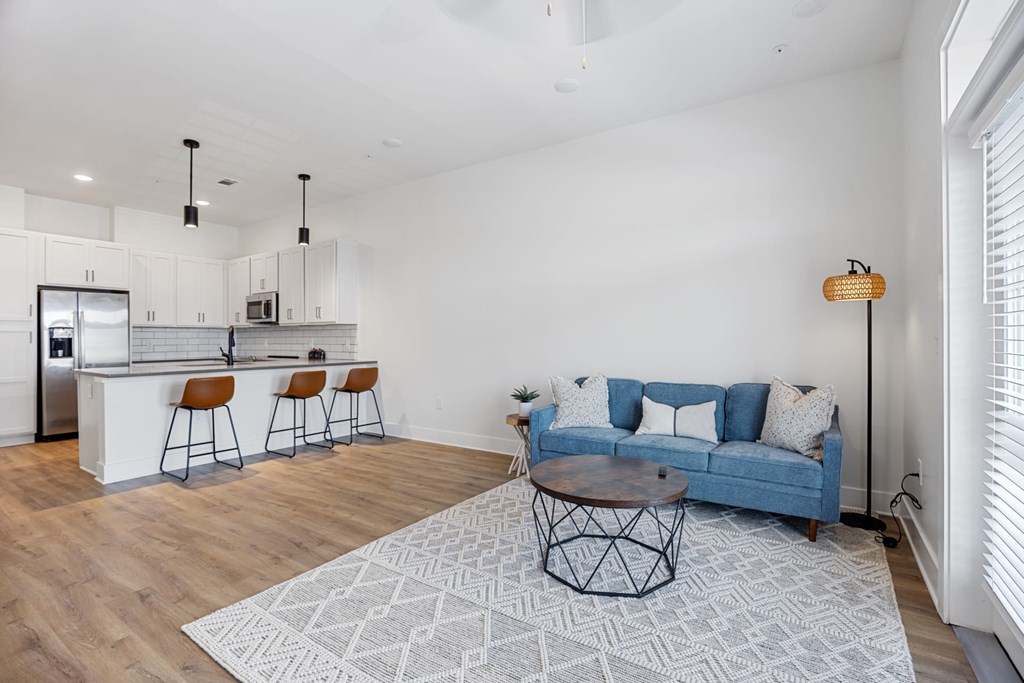 Modern Kitchen with Bar Seating, a Blue Sofa, and a Patterned Rug.