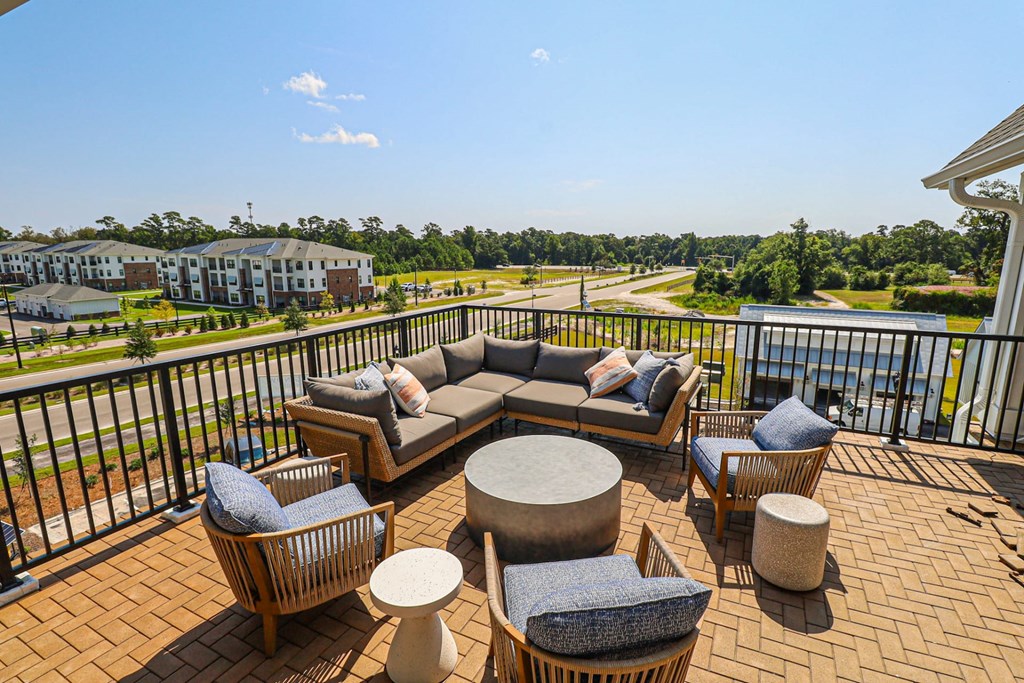 Outdoor Patio with a Couch, Chairs, and a Table with a View of a Road and Trees.