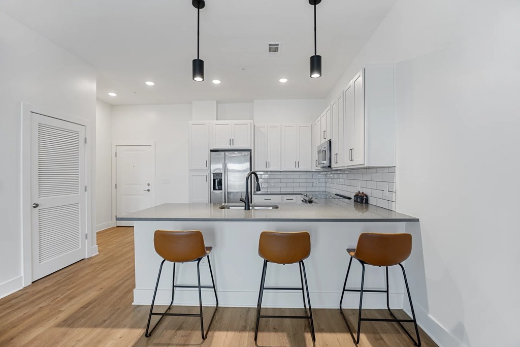 View of Kitchen with White Cabinets and an Island with Three Bar Stools.