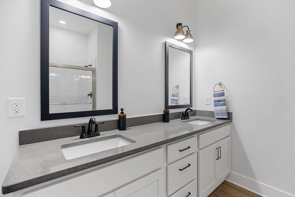 A Bathroom with Two Sinks, Two Mirrors, and Light Fixtures.