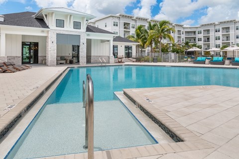 A swimming pool in front of a building with a white and beige exterior.