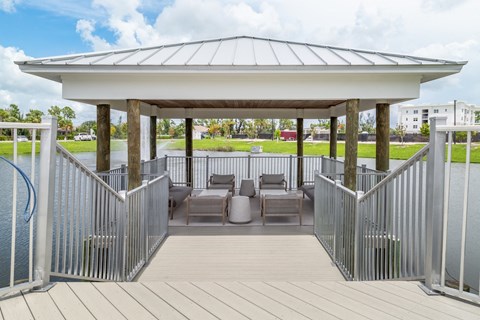 A gazebo with a white roof and wooden flooring is surrounded by a metal fence.