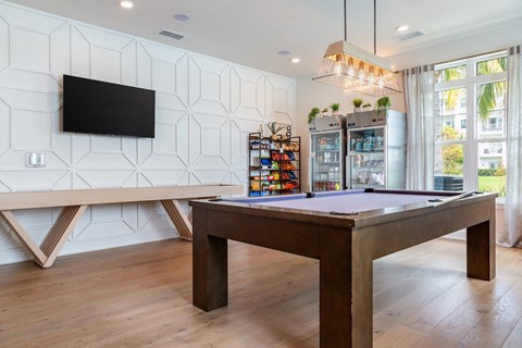 A room with a pool table and a tv on the wall.
