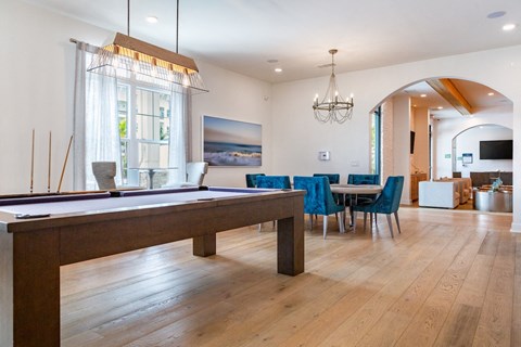 A billiard table is in the middle of a room with blue chairs.