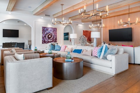 A modern living room with a grey sofa, a round coffee table, and a large painting on the wall.