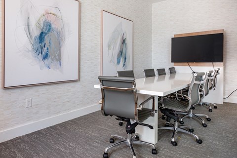 A conference room with a white table, chairs, and two paintings on the wall.