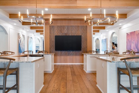 A modern kitchen with a large island and a TV mounted on the wall.