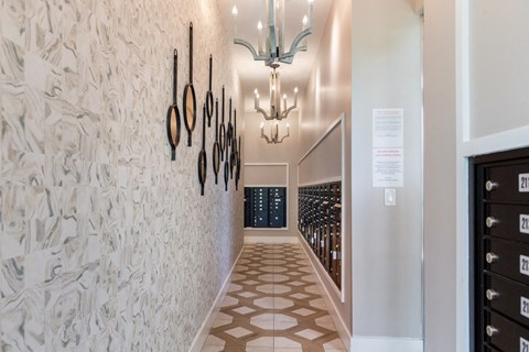 A hallway with a wall of wine bottles and a chandelier.