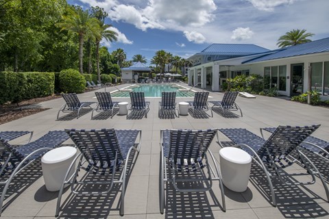 A pool surrounded by black chairs and tables.