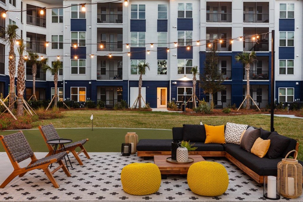a lounge area with a couch and chairs in front of an apartment building