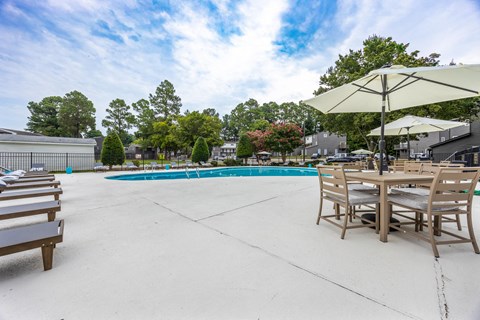 our apartments have a large pool and patio with tables and chairs