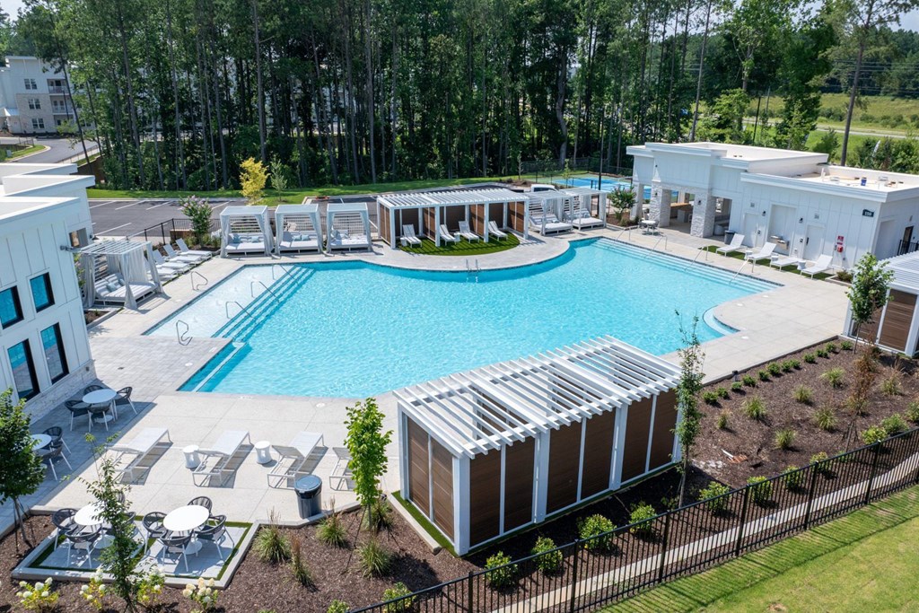 A large outdoor swimming pool surrounded by lounge chairs and trees.