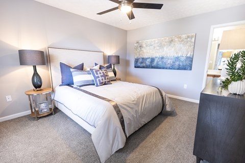 A bedroom with a bed, two lamps, and a painting on the wall.