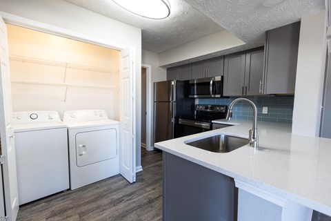 A kitchen with a white counter top and a black refrigerator.