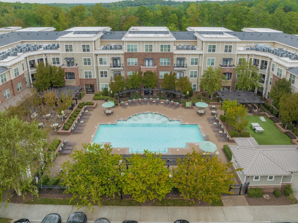 an aerial view of a large swimming pool in front of an apartment building
