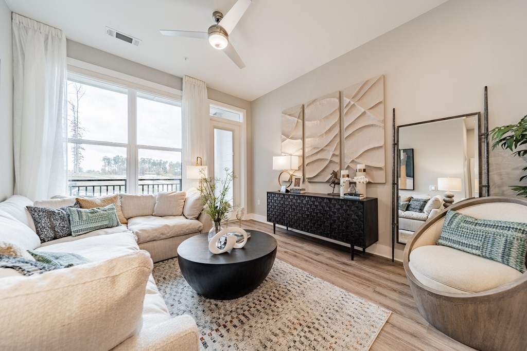 A living room with a white couch, a black coffee table, and a large mirror.