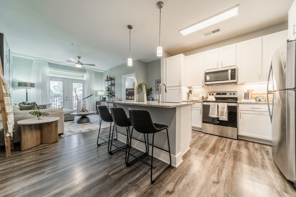 an open kitchen and living room with white cabinets and stainless steel appliances