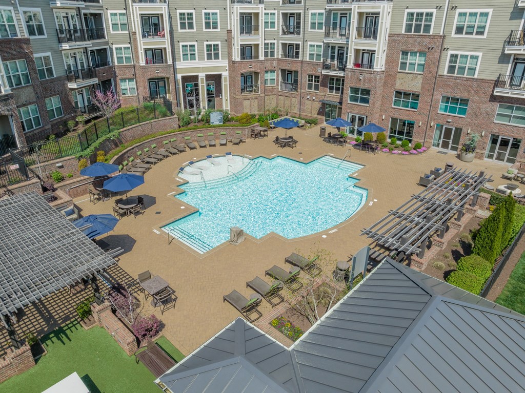 an aerial view of a resort style pool with lounge chairs and umbrellas in front of