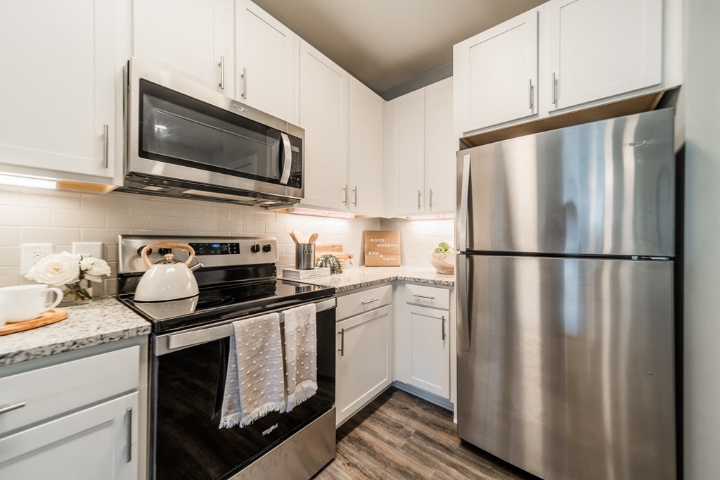 an updated kitchen with stainless steel appliances and white cabinets