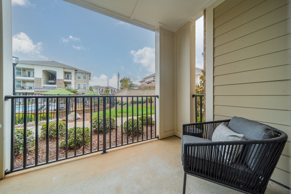 a balcony with a chair and a view of a yard and some houses