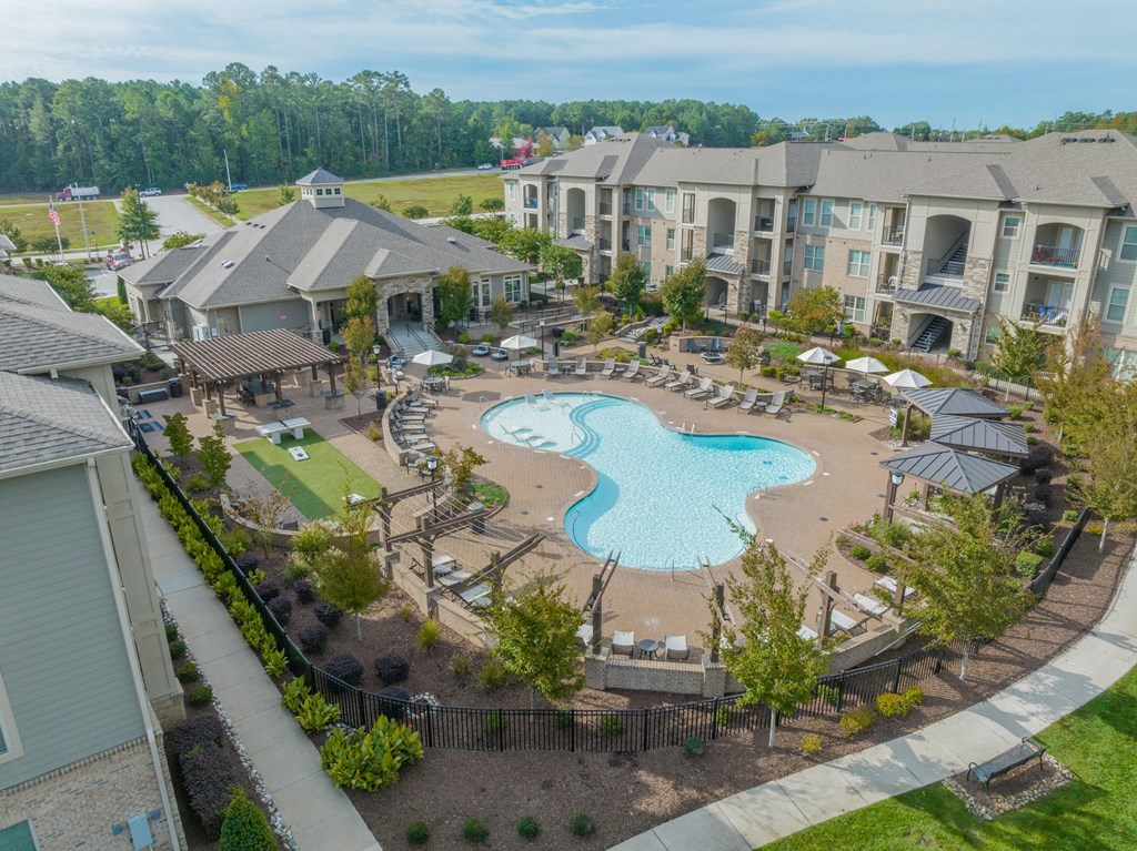 an aerial view of a swimming pool and patio area with apartment buildings