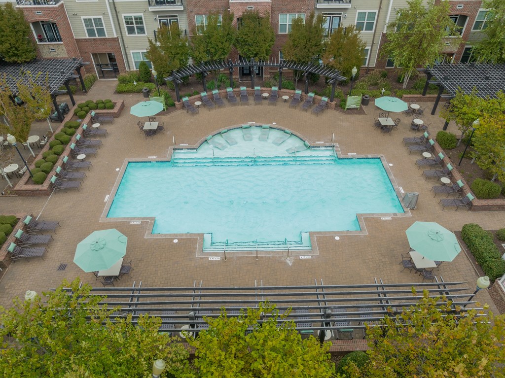 an aerial view of a large swimming pool with umbrellas and chairs around it