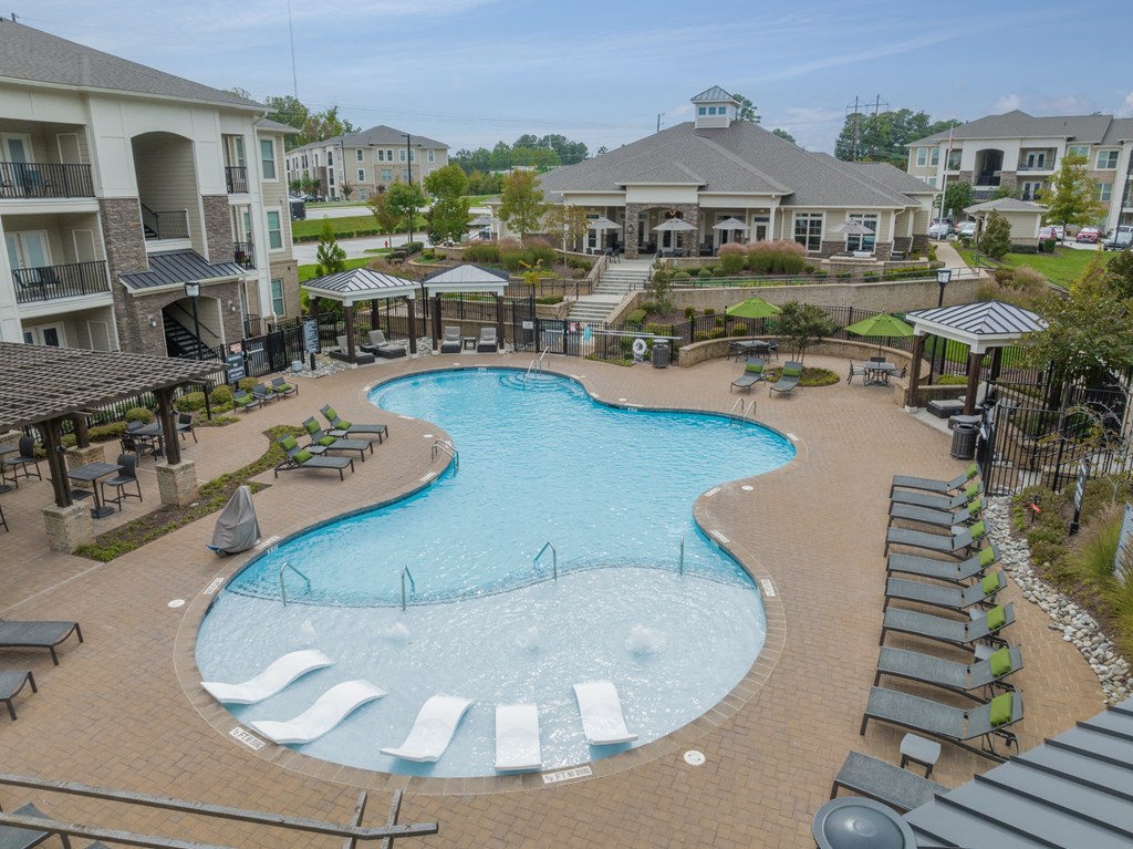 an aerial view of a large swimming pool with lounge chairs