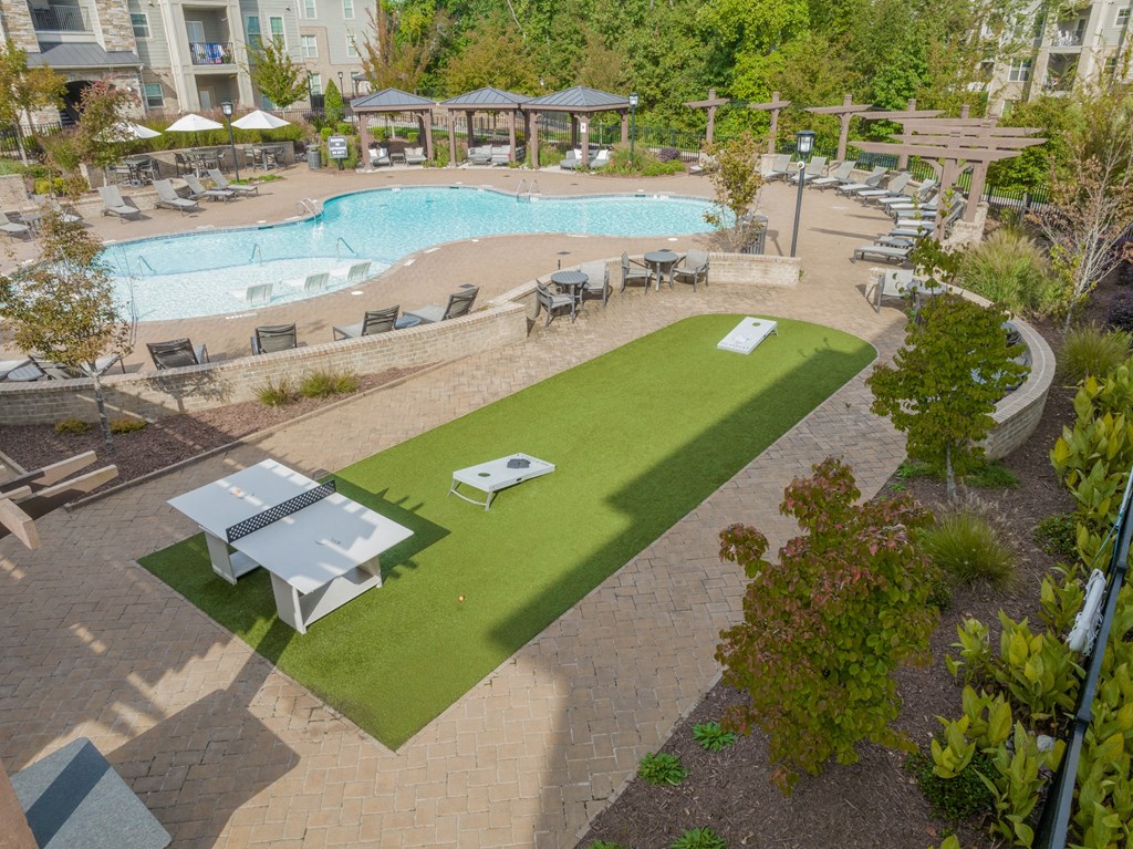 a view of a pool and a poolside patio with tables and umbrellas