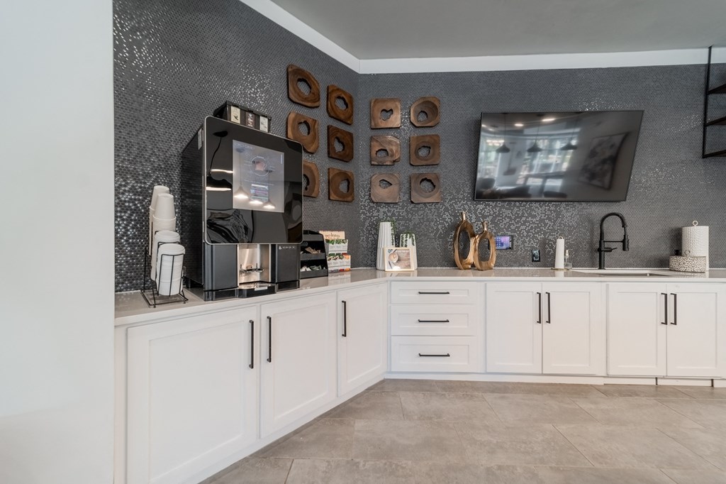 a kitchen with white cabinets and a tv on the wall
